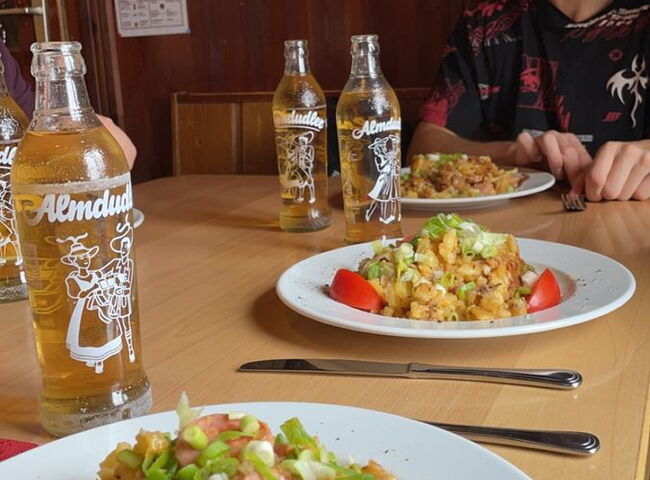 Spätzle serviert auf einem Teller, dazu Almdudler in Glasflaschen